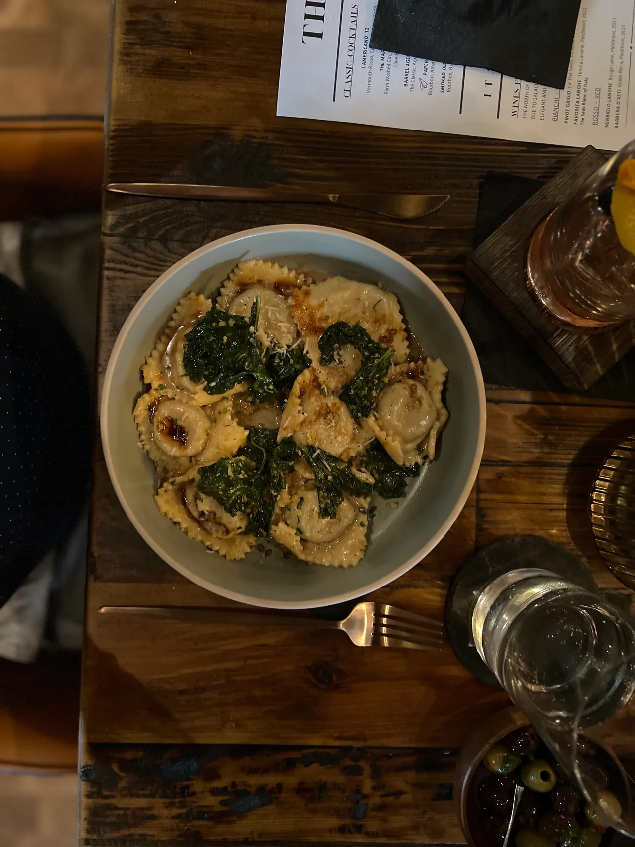 Overhead shot of ravioli with greens on a rustic wood table
